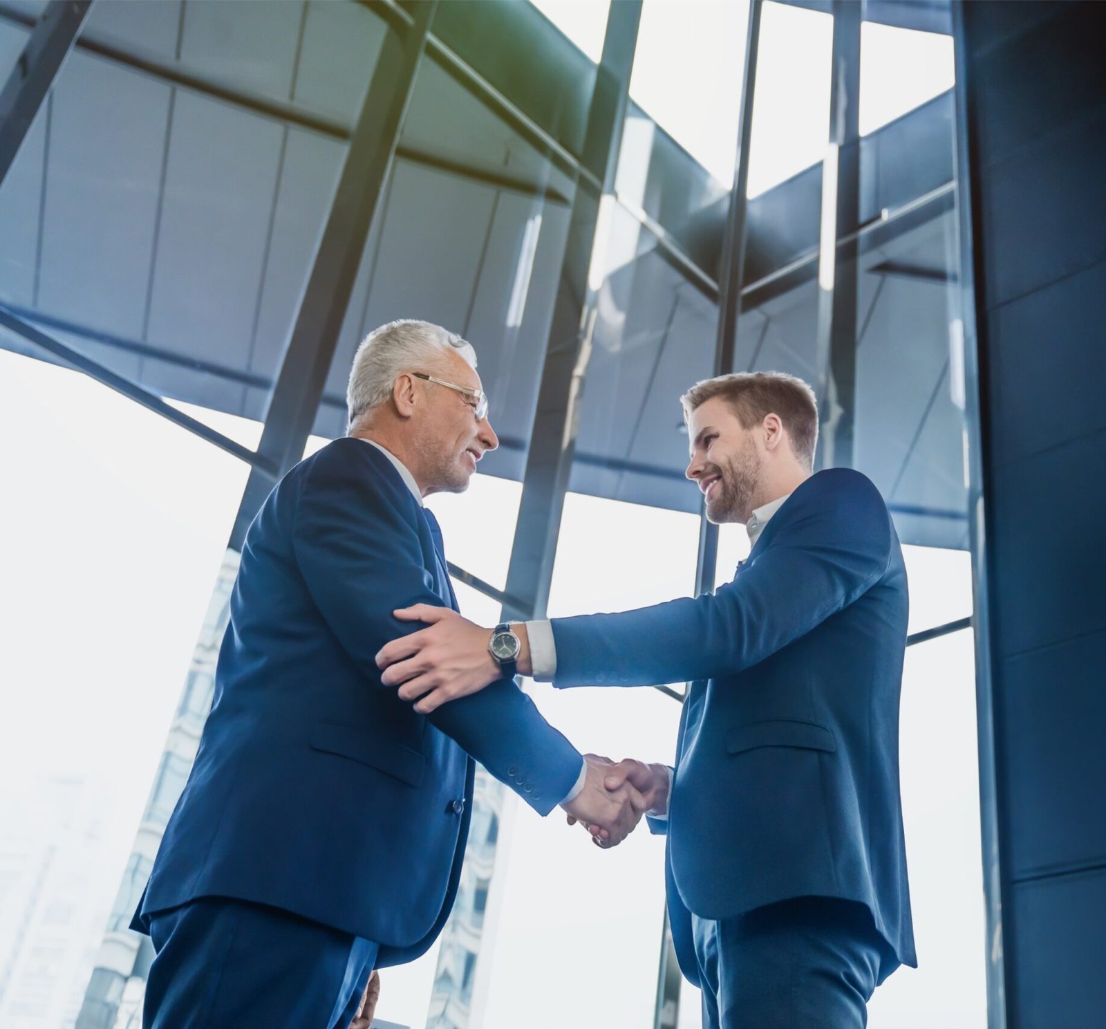 smiling-businessmen-greeting-each-other-while-standing-office-corridor
