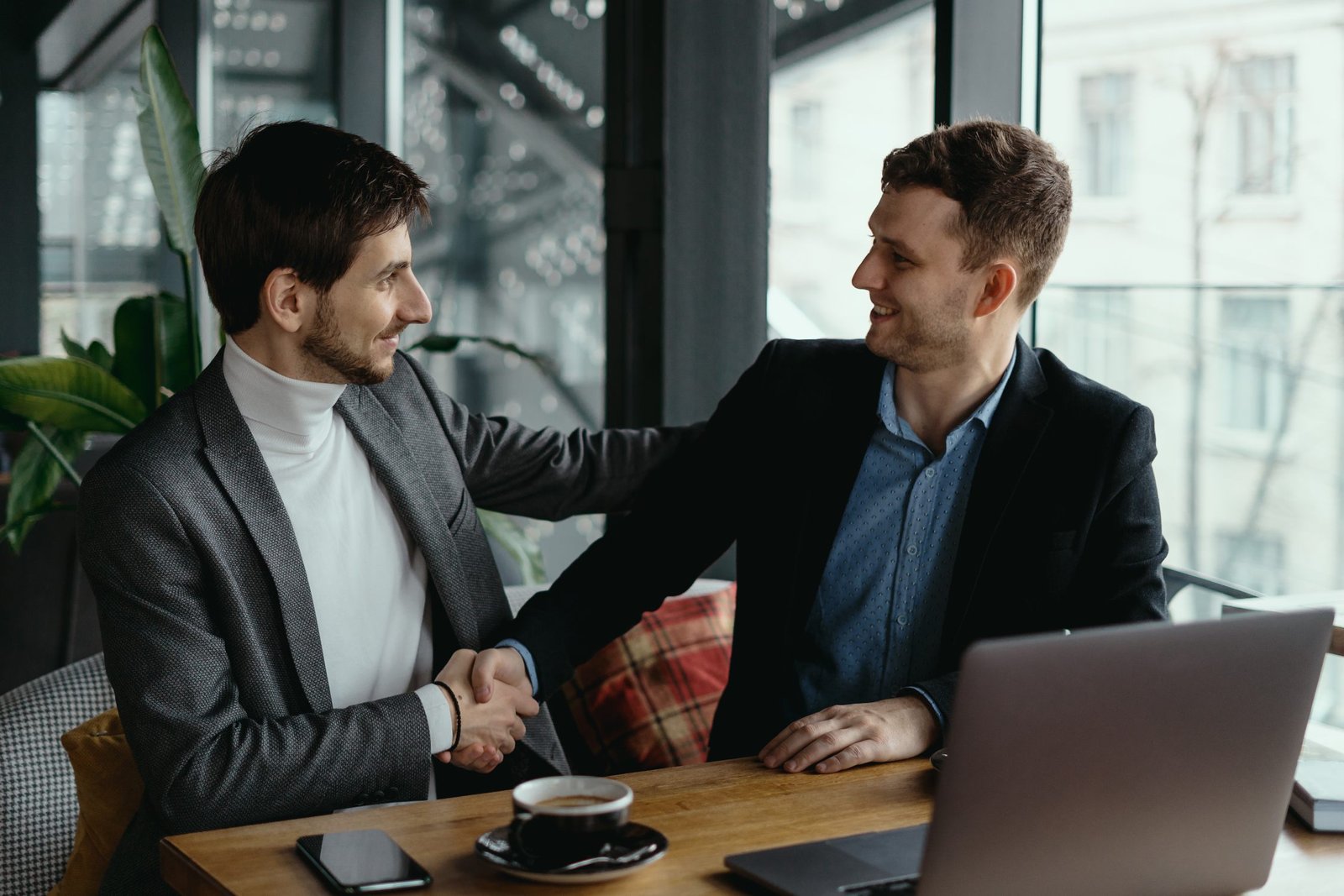 two-businessmen-shaking-hands-while-meeting-lobby (1)