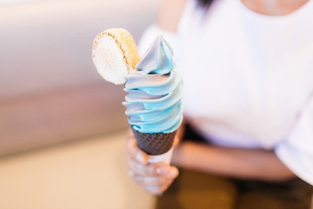 Woman holding blue ice cream cone.